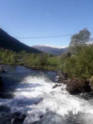 a river with rapids on it with mountains in the background at Naustvoll in Olden