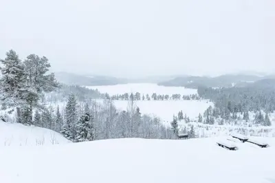a snow covered mountain with trees and a lake at Austbø Hotell in Rauland