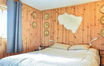 a bedroom with a bed and a wooden wall with clocks at Stunning Home In Haulandshella in Tveitevåg