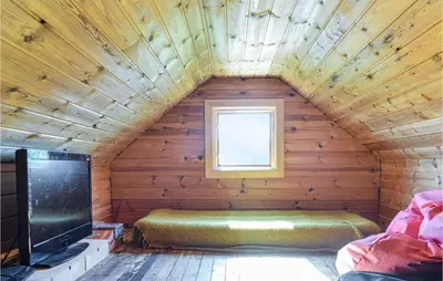 a room with a bed and a tv in a wooden room at Stunning Home In Haulandshella in Tveitevåg