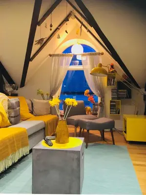 a living room with yellow furniture and a large window at Ålesund downtown loft room with shared bathroom in Ålesund