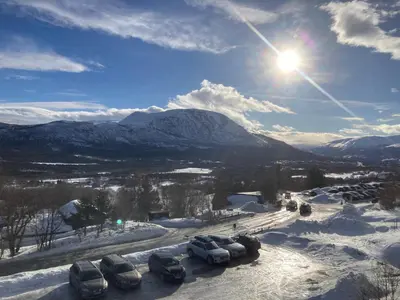 a group of cars parked in the snow with the sun at Oppdal Alpintun in Oppdal