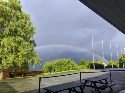 a rainbow in the sky with two picnic tables at Hardanger Hostel B&B in Lofthus