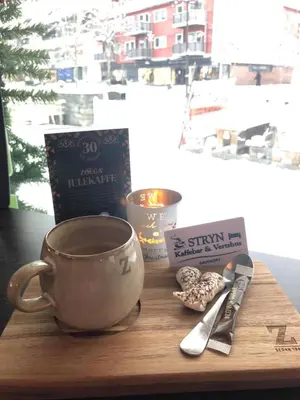 a coffee cup sitting on a wooden table next to a knife at Stryn Kaffebar & Vertshus in Stryn