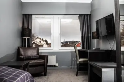 a bedroom with a bed and a desk and a window at Geilo Hotel in Geilo