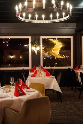 a dining room with white tables and chairs and a chandelier at Geilo Hotel in Geilo