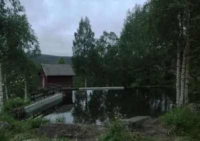 a house and a pond with a building and trees at Ivaregga Vinterstua in Tolga