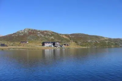 a house on a hill next to a body of water at Bergsjøstølen Fjellstue in Bergsjostolen