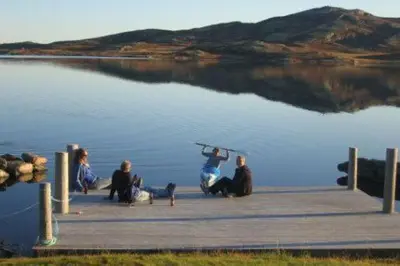 a group of people sitting on a dock on a lake at Bergsjøstølen Fjellstue in Bergsjostolen