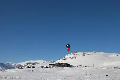 a person is flying a kite in the snow at Bergsjøstølen Fjellstue in Bergsjostolen