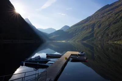 two boats are docked at a dock on a lake at Geirangerfjorden Feriesenter in Geiranger