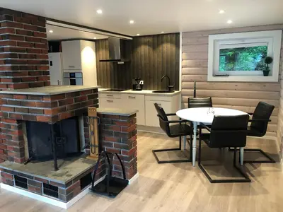 a kitchen and dining room with a fireplace and a table at Jolster sauna apartments in Skei