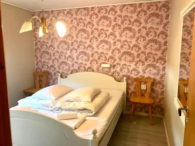 a bedroom with a white bed with a floral wallpaper at Villa Holmen 2 in Balestrand