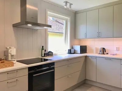 a kitchen with white cabinets and a sink and a window at Villa Holmen 2 in Balestrand