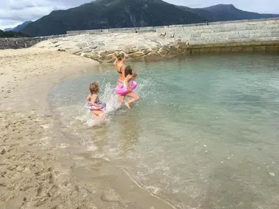 three girls are playing in the water on the beach at Villa Holmen 2 in Balestrand