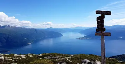 a wooden sign on top of a mountain overlooking a lake at Villa Holmen 2 in Balestrand