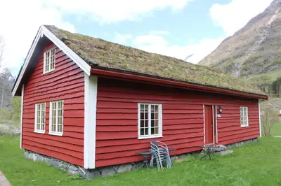 a red house with a grass roof on a field at Trollbu Aabrekk gard in Briksdalsbre