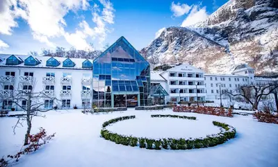 a hotel in the snow with a mountain in the background at Fretheim Hotel in Flåm