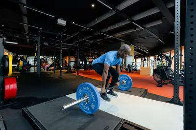a man in a gym squatting on a table with weights at Clarion Hotel Trondheim in Trondheim