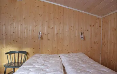 a bedroom with a bed and a chair and wooden walls at Stunning Home In Sjusjøen With Kitchen in Sjusjøen