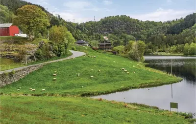 a herd of animals grazing on a grassy field next to a lake at 5 Bedroom Lovely Home In Seim in Seim