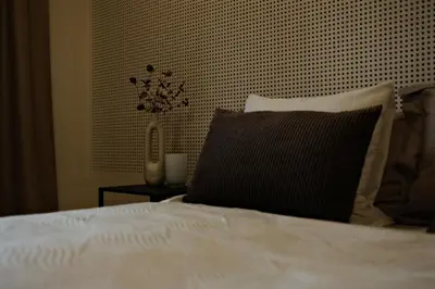 a bed with a black pillow and a vase on a table at Blue House Odda in Odda