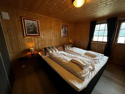 a bedroom with a large bed in a wooden room at Faleide Panorama Private Fjord View Cabin with Large Terrace in Stryn