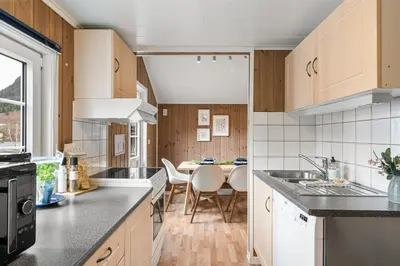 a kitchen with wooden cabinets and a table with chairs at Mikkelparken Ferietun in Kinsarvik