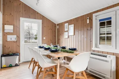 a dining room with a table and white chairs at Mikkelparken Ferietun in Kinsarvik
