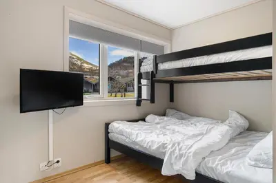 a bedroom with two bunk beds and a flat screen tv at Mikkelparken Ferietun in Kinsarvik
