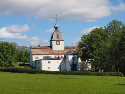a white church with a steeple on top of a field at Kårstua - Austrått Agroturisme in Austrått
