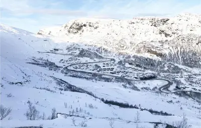a snow covered mountain with a town in the middle at Four-Bedroom Holiday Home In Roldal in Røldal