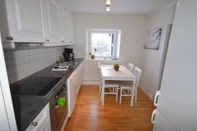 a kitchen with white cabinets and a table with chairs at Apartment between Ustaoset and Geilo in Geilo