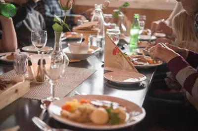 a group of people sitting at a table with plates of food at Dombås Hostel in Dombås