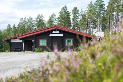 a log cabin with a red roof and blue windows at Dombås Hostel in Dombås
