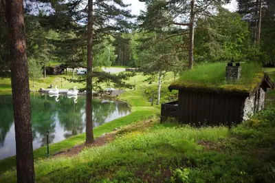 a house with a grass roof next to a river at Hunderfossen Cottages in Hafjell
