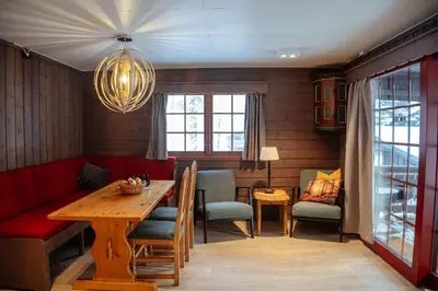 a dining room with a wooden table and chairs at Hunderfossen Cottages in Hafjell