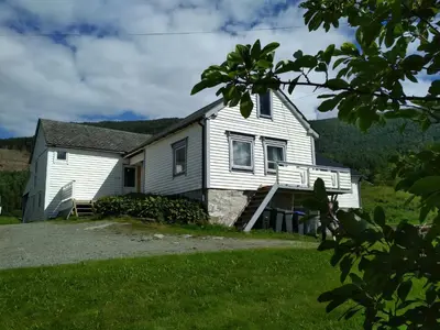 a white house with a porch on a grass field at 5 bedrooms, large apartment with nice view and nature in Herand
