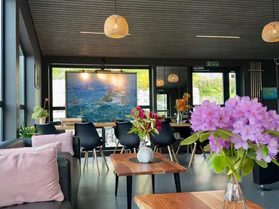 a dining room with tables and purple flowers in vases at Nordica Resort Florø in Florø