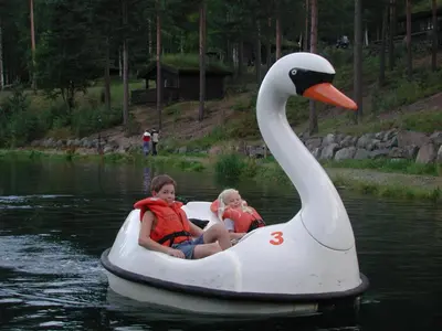 two children riding on an inflatable swan in the water at Hunderfossen Apartments in Hafjell