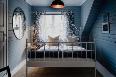 a blue room with a bed with a window at Fjærland Fjordstove Hotell - Huseby Hotelldrift AS in Fjarland