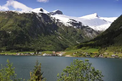 a lake in front of a snow covered mountain at Fjærland Fjordstove Hotell - Huseby Hotelldrift AS in Fjarland