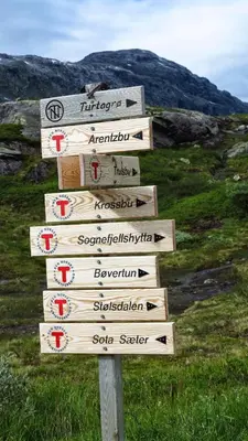 a wooden sign with arrows on a hill at Vassbakken Kro og Camping in Skjolden