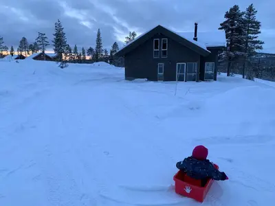 a person in a sled in the snow near a cabin at Trysilsetra 40 in Trysil
