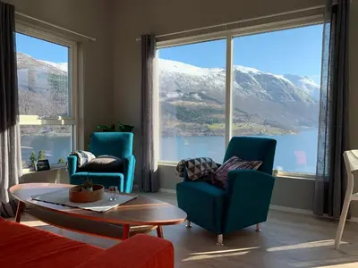 a living room with chairs and a table and a large window at Olden Fjord Apartments in Olden