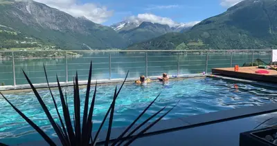 two people in a swimming pool with a view of mountains at Olden Fjord Apartments in Olden