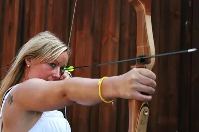 a woman is aiming a bow and arrow at Trolltunga Camping in Odda