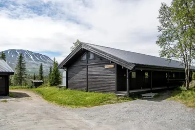 a black building with a mountain in the background at Kvitåvatn Fjellstue in Gaustablikk