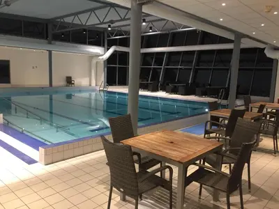a swimming pool with tables and chairs in front of it at Finnøya with 180* Atlantic veiw in Finnøy