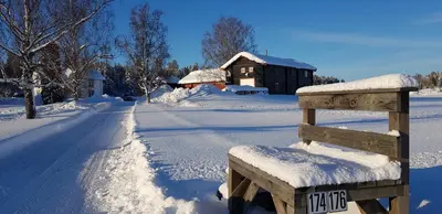 a snow covered bench in front of a house at Drolsum Gård in Vikersund